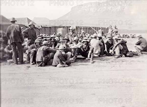 Military compound below the Platberg Mountain. Uniformed British soldiers in the Second Boer War (1899-1902) sit outside a military compound in a valley below the Platberg Mountain. Harrismith, Orange River Colony (Free State), South Africa, circa 1901. Harrismith, Free State, South Africa, Southern Africa, Africa.