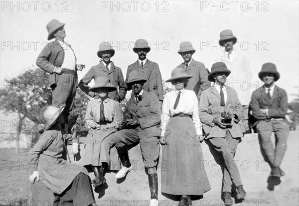 A European hunting party, 1911. A group of European friends pose for a photograph before embarking on a hunting expedition on the Indus River. Both the men and women wear shirts and ties with solatopi hats, and one of the group holds a camera. Probably Sind, India (Sindh, Pakistan), December 1911., Sindh, Pakistan, Southern Asia, Asia.