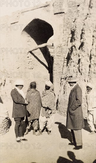 Colonial officer visiting a tomb. Sir Henry Staveley Lawrence (left), Acting Governor of Bombay, and his European friend stand at the gateway to a tomb, conversing with two Indian men in traditional dress. Hyderabad, Hyderabad State (Andhra Pradesh), India, circa 1926. Hyderabad, Andhra Pradesh, India, Southern Asia, Asia.