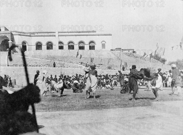 Wrestling match in Sukkur. A number of wrestlers fight each other in front of seated spectators during a public wrestling match. Sukkur, Sind, India (Sindh, Pakistan), circa 1908. Sukkur, Sindh, Pakistan, Southern Asia, Asia.