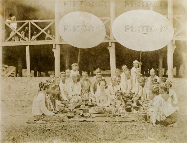 The Saopha of Wuntha's wife. Outdoors portrait of the Saopha of Wuntho's wife and young son, surrounded by female attendants. The group kneel on a mat laden with lacquerware tiffin boxes in the shade of two large parasols. Saopha Maung Aung Myat had taken over leadership of Wuntho in 1881, although the state remained outside British administration until it was formally annexed in 1892. Sagaing, Burma (Myanmar), circa 1891., Sagaing, Burma (Myanmar), South East Asia, Asia.
