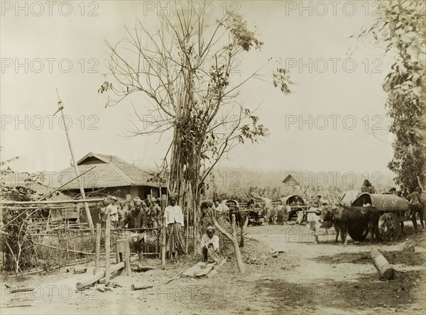 Soldiers visit a Burmese village. British and Indian soldiers visit a Burmese village. Possibly a mix of British Army and Military Police officers, the men were involved in a campaign to suppress Burmese rebels in Wuntho State (Sagaing Division). A local man works a wooden lathe, whilst others sit inside carts pulled by bullocks. Youngma, Burma (Myanmar), 1891. Youngma, Sagaing, Burma (Myanmar), South East Asia, Asia.
