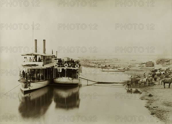 Ferries on the Irrawaddy River. Two ferries containing soldiers from the Second Mountain Battery of the Royal Artillery are moored alongside a sandy bank of the Irrawaddy River. The company was involved in a campaign to suppress Burmese rebels in Wuntho State (Sagaing Division). Htagaing, Burma (Myanmar), circa 1891. Htagaing, Sagaing, Burma (Myanmar), South East Asia, Asia.