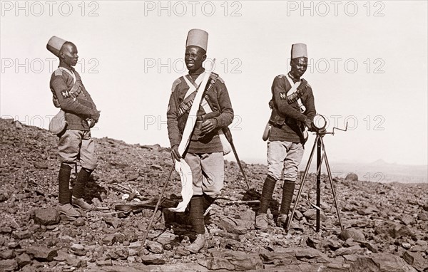 Sudanese signalmen in the Anglo-Egyptian army. Three Sudanese signalmen in the Anglo-Egyptian army operate a mirror signalling device on rocky ground. An original caption labels this image as: 'Battlefield, Omdurman', and suggests that it may have been taken around the time of the Battle of Omdurman (1898), which saw Mahdist Sudanese forces defeated by the British under the command of Lord Kitchener. Omdurman, Sudan, circa 1898. Omdurman, Khartoum, Sudan, Eastern Africa, Africa.
