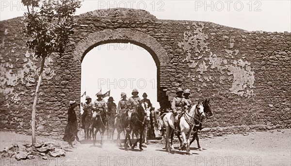 The Duke of Connaught visits Omdurman, 1899. The Duke of Connaught and his entourage, all dressed in military uniform, ride through a stone archway on horseback. The Duke visited Omdurman in 1899, shortly after the Battle of Omdurman (1898), which saw Mahdist Sudanese forces defeated by the British under the command of Lord Kitchener. Omdurman, Sudan, circa 1899. Omdurman, Khartoum, Sudan, Eastern Africa, Africa.