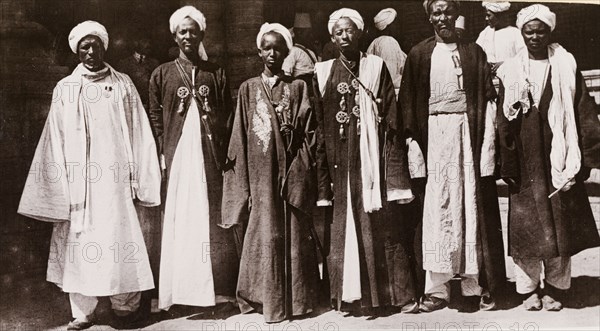Six Gimma 'sheikhs'. Six Gimma 'sheikhs' pose for a group portrait. They wear traditional dress including 'thobs' (ankle-length garments with long sleeves), 'bishts' (loose-fitting outer cloaks) and turbans. Blue Nile State, Sudan, circa 1910., Blue Nile, Sudan, Eastern Africa, Africa.