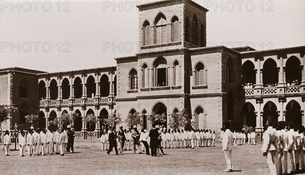 Student inspection at Gordon College, Khartoum. Lines of Sudanese students, dressed in a uniform of white suits and fez hats, wait for an inspection by military officers in a courtyard outside Gordon College. Khartoum, Sudan, circa 1910. Khartoum, Khartoum, Sudan, Eastern Africa, Africa.