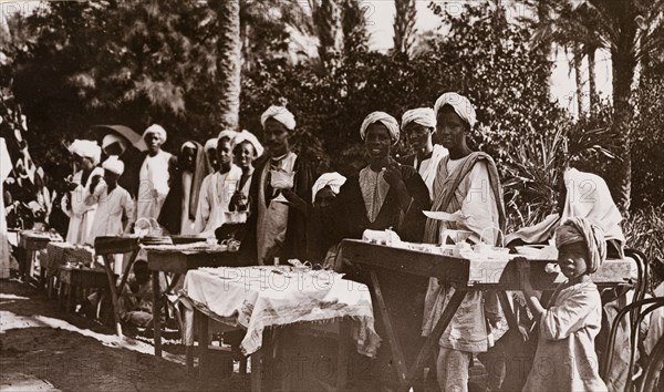 Street traders selling silverware, Khartoum. A line of Sudanese street traders, many of them adolescents or children, display a variety of silverware on their stalls. Khartoum, Sudan, circa 1910. Khartoum, Khartoum, Sudan, Eastern Africa, Africa.