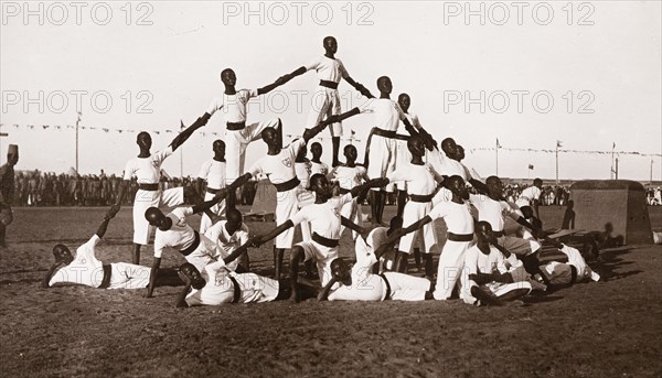 Sudanese military cadets. A group of young Sudanese army cadets, dressed in white uniforms, form a human pyramid during an outdoor display at a military school. Khartoum, Sudan, circa 1910. Khartoum, Khartoum, Sudan, Eastern Africa, Africa.