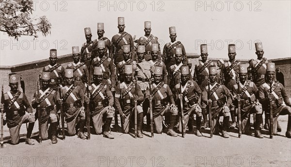Third Battalion of Egyptian Army. Sudanese soldiers in the Third Battalion of the Egyptian Army pose for the camera dressed in full military regalia: those in the front row hold rifles. Sudan, circa 1910. Sudan, Eastern Africa, Africa.