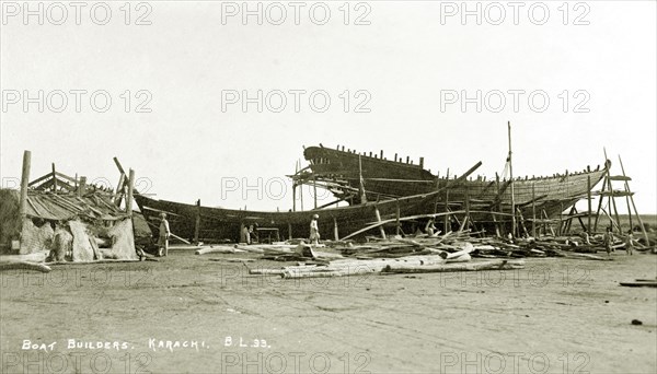Boat builder's yard in Karachi. Two boats encased in scaffolding undergo construction at a boat builder's yard in Karachi. Karachi, India (Pakistan), circa 1910. Karachi, Sindh, Pakistan, Southern Asia, Asia.