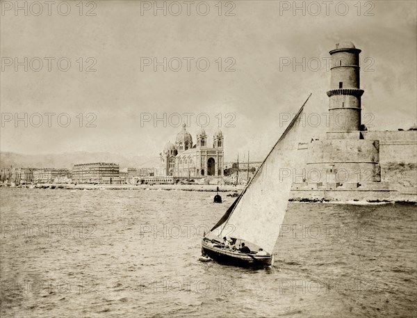 Vieux Port, Marseille. A small boat sails near to the entrance of Vieux Port at Marseille. The city's grandiose, domed cathedral appears in the background. Marseille, France, 1901. Marseille, Provence-Alpes-Cote d'Azur, France, Western Europe, Europe .