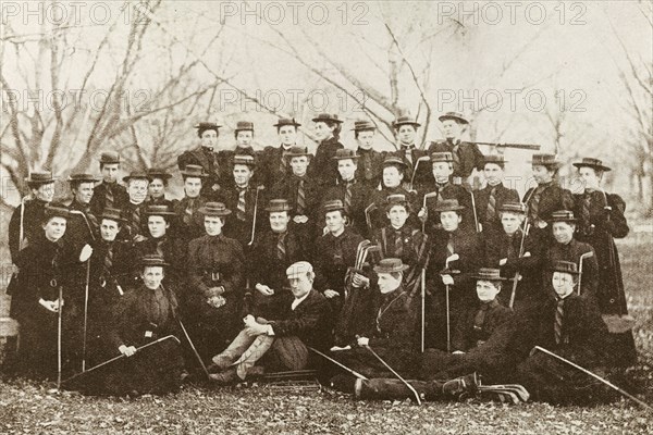 New Zealand ladies' golf teams. A photograph printed in 'The Sketch' newspaper features women from the Christchurch and Dunedin ladies' golf teams, posing for a group portrait with their golf clubs. The women wear a uniform of dark dresses, striped ties and boater hats. Probably Christchurch, New Zealand, 1895. Christchurch, Canterbury, New Zealand, New Zealand, Oceania.