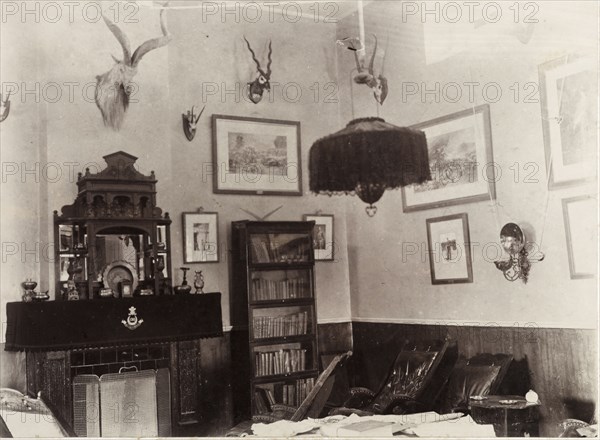 Ante room in a British Army mess building. Interior shot of an ante room in a British Army mess building, used by off-duty soldiers as a place to relax and socialise. Framed pictures and mounted antelope skulls adorn the walls, whilst padded chairs surround a table sprawling with papers. Chaman, Baluchistan, India (Balochistan, Pakistan), 1905. Chaman, Balochistan, Pakistan, Southern Asia, Asia.