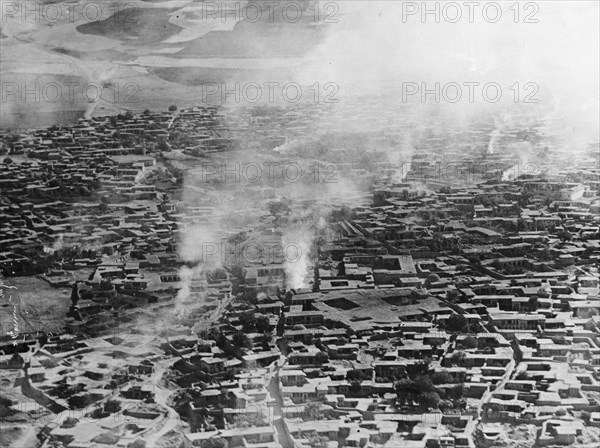 Smoke rises from Sulaymaniyah. Smoke rises from several points across the Kurdistan city of Sulaymaniyah. An original caption suggests the town had recently been bombed by the British Royal Air Force: possibly a reference to the RAF bombing of Sheikh Mahmud's house in December 1923, when he proclaimed himself King of Kurdistan in defiance of British control. Sulaymaniyah, British Mandate of Mesopotamia (Iraq), circa December 1923. Sulaymaniyah, Sulaymaniyah, Iraq, Middle East, Asia.
