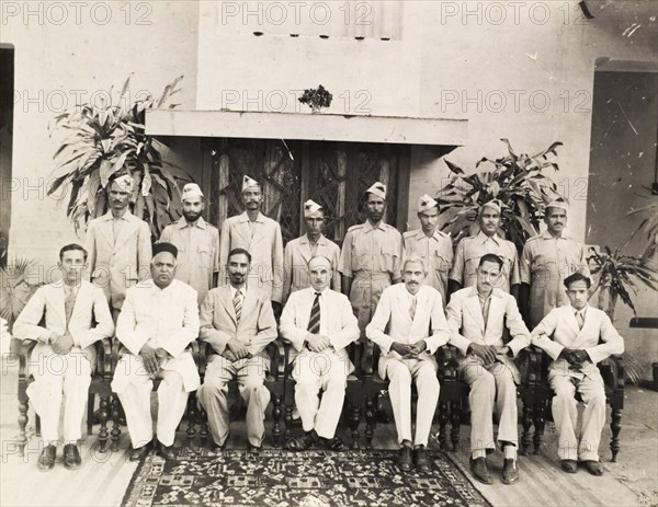 The Central Intelligence Office, Lucknow. Group portrait of the United Provinces and Ajmer division of the Central Intelligence Office. A British man identified as 'E. Walsh', sits at the centre of the front row with a number of Indian officials, in front of a line of uniformed 'daffadars' from the British Indian Army. Lucknow, United Provinces (Uttar Pradesh), India, 19 May 1945. Lucknow, Uttar Pradesh, India, Southern Asia, Asia.