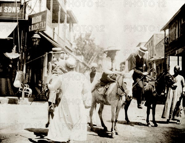 The Lawley children ride donkeys at Port Said. The Lawley children, 'Ned' (Richard) and his older sister Ursula, are supervised by their tutor, Mr. Jose, as they ride donkeys in the centre of town. Port Said, Egypt, circa April 1901. Port Said, Port Said, Egypt, Northern Africa, Africa.
