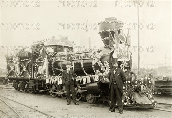 Royal train at Perth. Two men stand beside a locomotive, decorated with flowers and bunting for the arrival of the Duke and Duchess of Cornwall and York (later King George V and Queen Mary) from Albany. Perth, Australia, July 1901. Perth, West Australia, Australia, Australia, Oceania.