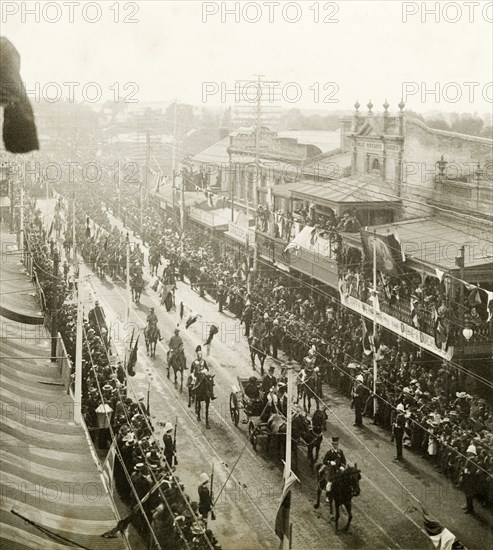 Royal parade through Perth, 1901. A horse-drawn carriage containing the Duke and Duchess of Cornwall and York (later King George V and Queen Mary), parades through the streets of Perth, watched by an eager crowd of spectators who are held back by barriers. Perth, Australia, July 1901. Perth, West Australia, Australia, Australia, Oceania.