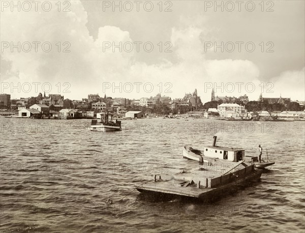 View of Perth from Swan River. View of Perth taken from Swan River, showing a number of tug boats and barges bobbing about in the water. Perth, Australia, 1901. Perth, West Australia, Australia, Australia, Oceania.
