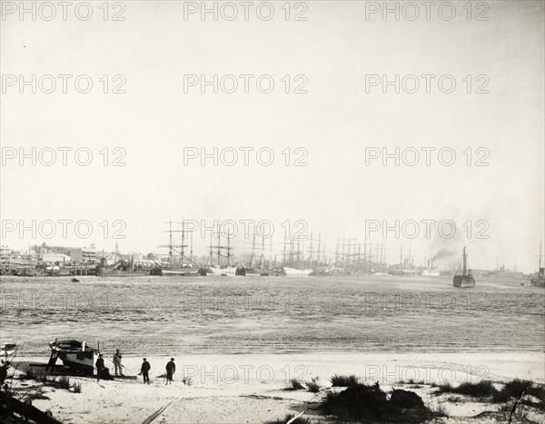 Steam ships in harbour at Fremantle. Steam-assisted sailing ships and steamships sit in the harbour at Fremantle. A grounded row boat rests on a sandy shore in the foreground. Fremantle, Australia, 26 July 1901. Fremantle, West Australia, Australia, Australia, Oceania.