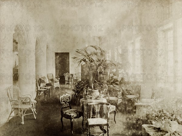 Ballroom seating at Government House, Perth. Interior shot of the ballroom seating area inside Perth's Government House. Wooden and cane chairs are dotted around tables decorated with potted plants. Perth, Australia, circa 1901. Perth, West Australia, Australia, Australia, Oceania.