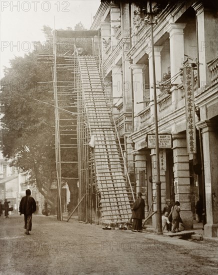Staircase for a coffin. A coffin sits at the top of a makeshift staircase attached to the exterior of a three-storey building. Staircases such as these were designed to convey the body of the deceased to the street without using the internal stairwell, an act that was considered to invoke bad fortune. Probably Hong Kong, China, circa 1903. Hong Kong, Hong Kong, China, People's Republic of, Eastern Asia, Asia.