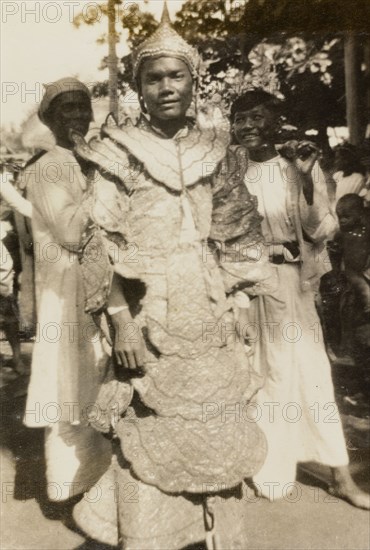 A 'nat kadaw' at the Taungbyon Festival. Portrait of a 'nat kadaw' (spiritual performer), dressed in an elaborate, ruffled costume and pointed hat at the Buddhist Taungbyon Festival. Wagaung, Burma (Myanmar), August 1924. Wagaung, Mandalay, Burma (Myanmar), South East Asia, Asia.