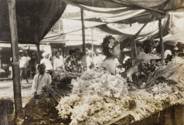 Flower stall at Taungbyon Festival. A Burmese woman arranges bundles of flowers on a stall at the Buddhist Taungbyon Festival. Celebrated annually in July or August, this is one of the most important 'nat pwe' (spirit) festivals in Burma (Myanmar). Wagaung, Burma (Myanmar), August 1924. Wagaung, Mandalay, Burma (Myanmar), South East Asia, Asia.