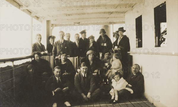 Enroute to Burma aboard the S.S. Amarapura. A number of European passengers and two ship's officers pose for a group portrait whilst drinking tea on the deck of S.S. Amarapura, enroute from England to Burma (Myanmar). Location unknown, February 1926.