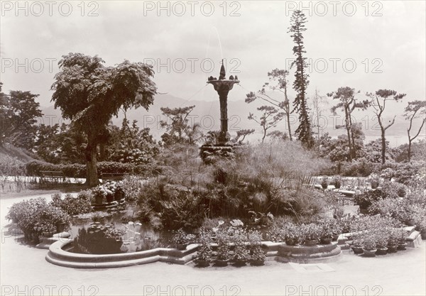 Fountain in Hong Kong's Botanical Gardens. A water fountain surrounded by foliage forms the centrepiece of an ornmanetal pond in Hong Kong's Botancial Gardens. Hong Kong, China, circa 1903. Hong Kong, Hong Kong, China, People's Republic of, Eastern Asia, Asia.