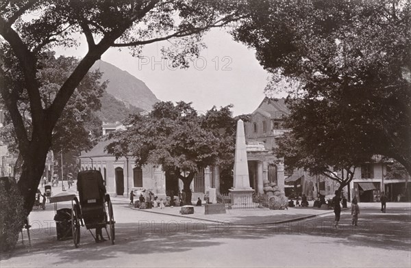 Market square in Wan Chai. A view of a market square at the foot of Morrison Hill in Wan Chai, where only a couple of street traders have set their stalls up by a tall, stone monument, which stands in the centre. Wan Chai, Hong Kong, China, circa 1903. Wan Chai, Hong Kong, China, People's Republic of, Eastern Asia, Asia.