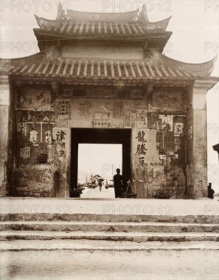 Gateway to Kowloon Harbour. A gateway, decorated with a pagoda-style roof, leads to Kowloon Harbour. Half-torn posters covered with Chinese script remain pasted to its facade. Kowloon, Hong Kong, China, circa 1903. Kowloon, Hong Kong, China, People's Republic of, Eastern Asia, Asia.