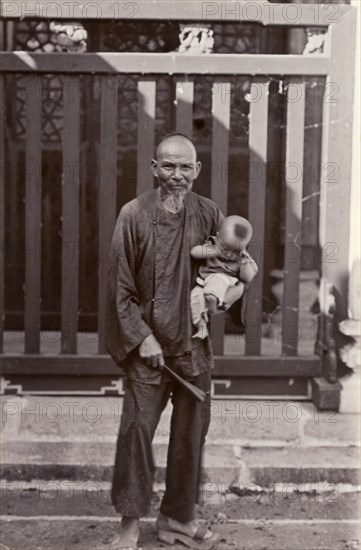 An elderly Cantonese man holds his great-grandson. Portrait of an elderly Cantonese man, holding his great grandson in the crook of one arm. Canton, Canton Province (Guangzhou, Guangdong), China, circa 1905. Guangzhou, Guangdong, China, People's Republic of, Eastern Asia, Asia.