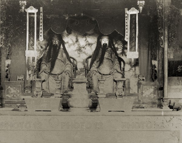Statues of deities inside a Chinese Joss house. The statues of two Chinese deities ('Joss'), possibly idols of the Jade Emperor, sit side-by-side at the altar of a Joss house. Hong Kong, China, circa 1905., Hong Kong, China, People's Republic of, Eastern Asia, Asia.