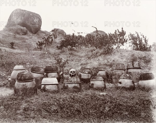 Chinese burial urns. A number of burial urns, containing exhumed human bones, are grouped together on a hillside. Living relatives considered their fortunes to be directly linked to the positioning of the urns, and favoured locations with a positive 'feng shui' (natural harmony). Probably Hong Kong, China, circa 1905. China, People's Republic of, Eastern Asia, Asia.