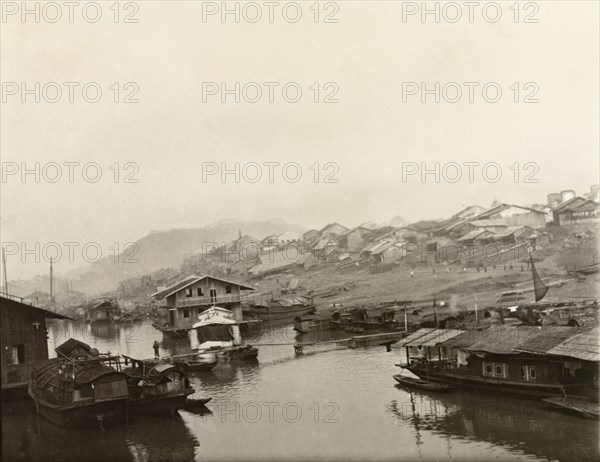Houseboats at Wuchow. Several houseboats are moored along the banks of the Xijiang River at Wuchow (Wuzhou). A number of roughly-built houses comprise a shanty town leading down to the water's edge in the distance. Wuchow (Wuzhou), Guangxi Province, China, circa 1906. Wuzhou, Guangxi, China, People's Republic of, Eastern Asia, Asia.