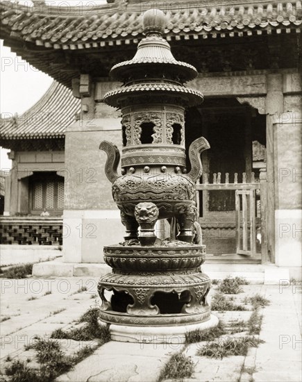 Incense burner at a Buddhist temple in China. A large, ornamental incense burner stands in the courtyard of a Buddhist temple. Peking (Beijing), China, circa 1910. Beijing, Beijing, China, People's Republic of, Eastern Asia, Asia.