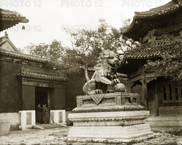 Statue of a lion at a Buddhist temple in China. An ornamental statue of a lion stands in the courtyard of a Buddhist temple, its clawed paw resting on a globe. Peking (Beijing), China, circa 1910. Beijing, Beijing, China, People's Republic of, Eastern Asia, Asia.