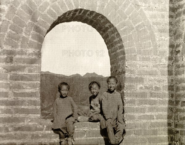 Children at a watchtower on the Great Wall of China. Three children pose for the camera in the arched window of a brick watchtower on the Great Wall of China. Probably Hebei Province, China, circa 1910., Hebei, China, People's Republic of, Eastern Asia, Asia.