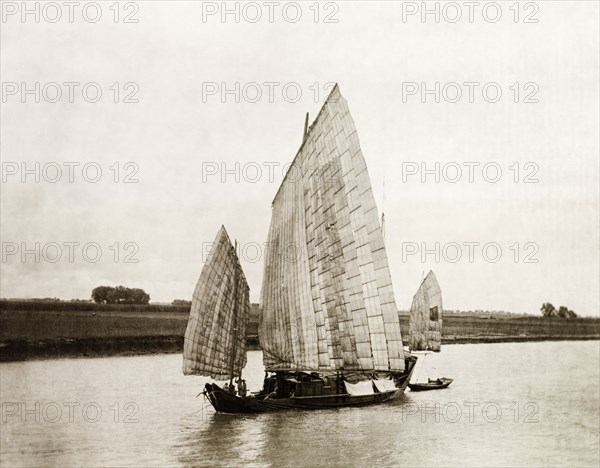 A junk transports salt on the Yangtze River. A Chinese junk with sails made from woven bamboo, transports salts on the Yangtze River. China, circa 1910. China, People's Republic of, Eastern Asia, Asia.