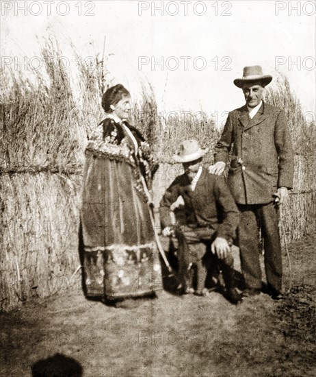 Sir Arthur Lawley with his wife and brother. Sir Arthur Lawley (1860-1932) poses for a photograph with his brother, Algernon Lawley, fifth Baron Wenlock (right), and his wife, Lady Annie Lawley, who wears a robe intended for the Queen Regent of Swaziland. Swaziland, 1904. Swaziland, Southern Africa, Africa.