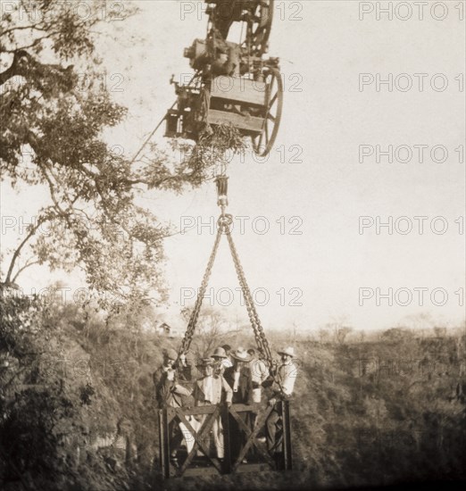 A cable system across the Zambezi gorge. A group of British passengers make the return journey across the Zambezi gorge at Victoria Falls in a cage attached to a cable system. Matabeleland, Rhodesia (Matabeleland North, Zimbabwe), circa 1904., Matabeleland North, Zimbabwe, Southern Africa, Africa.