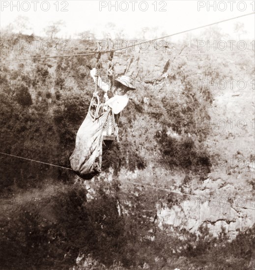 Lady Lawley crosses the Zambezi gorge. Lady Annie Lawley, the wife of Sir Arthur Lawley, Lieutenant-Governor of the Transvaal, crosses the Zambezi gorge at Victoria Falls in a chair lift attached to a cable system. Matabeleland, Rhodesia (Matabeleland North, Zimbabwe), circa 1904., Matabeleland North, Zimbabwe, Southern Africa, Africa.