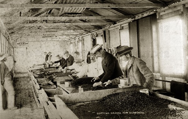 Sorting gravel for diamonds'. European workers at the De Beers diamond mine sift through trays of gravel looking for diamonds. Kimberley, South Africa, circa 1896. Kimberley, North Cape, South Africa, Southern Africa, Africa.