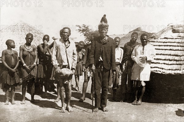 Chief Sekombo. Matabele (Ndebele) Chief Sekombo poses outside village huts with his witch doctor, wives and sub-chiefs. Rhodesia (Zimbabwe), circa 1897. Zimbabwe, Southern Africa, Africa.
