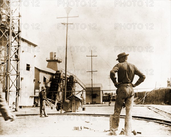 Diamond mine labourers at Kimberley. Labourers at the Kimberley diamond mine stand beside a small gauge rail track, waiting for mine carts to arrive at the factory. Kimberley, South Africa, circa 1896. Kimberley, North Cape, South Africa, Southern Africa, Africa.