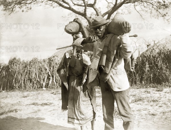 Couple carrying sacks. An African man and woman carry sacks along a rural road. Probably Bechuanaland (Botswana), circa 1896. Botswana, Southern Africa, Africa.