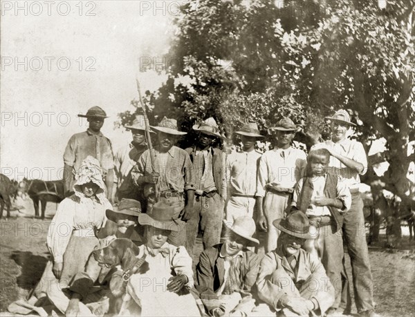 Captain Lawley with fellow travellers. Captain Arthur Lawley (1860-1932) (second from left, front row) poses for a group portrait with fellow European and African travellers during an overland journey from South Africa to Rhodesia. Accompanied by Earl Grey (1851-1917), he was travelling with relief forces and supplies to Bulawayo, which had been besieged during the Matabele rebellion. Probably Bechuanaland (Botswana), circa March 1896. Botswana, Southern Africa, Africa.