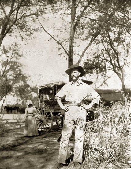 Captain Lawley travels to Bulawayo. Captain Arthur Lawley (1860-1932) stands with his hands on his hips smoking a pipe during an overland journey from South Africa to Rhodesia. Accompanied by Earl Grey (1851-1917), he was travelling with relief forces and supplies to Bulawayo, which had been besieged during the Matabele rebellion. Probably Bechuanaland (Botswana), circa March 1896. Botswana, Southern Africa, Africa.